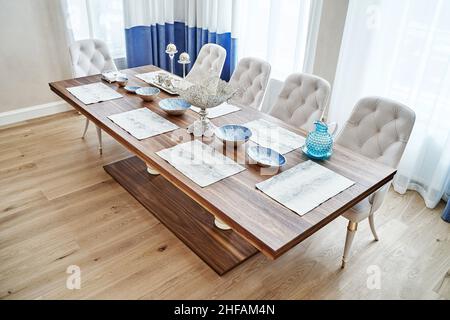 Table de salle à manger luxueuse et vintage en bois de noyer et de placage, cadre festif et fauteuils près de la fenêtre dans une chambre spacieuse Banque D'Images