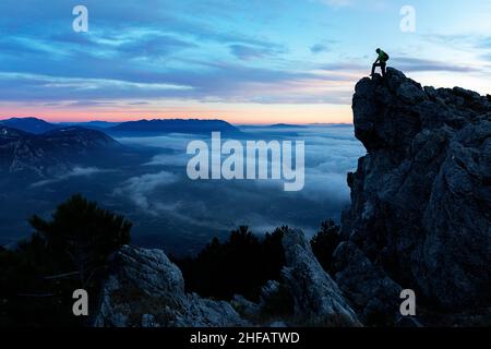 Homme debout sur la formation rocheuse avec le beau panorama de la vallée de Vipava en Slovénie, au coucher du soleil, regardant du sommet de la montagne de Caven Banque D'Images