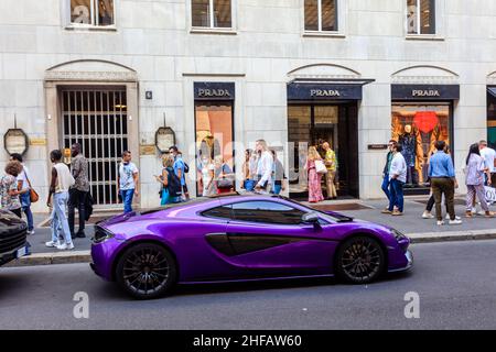 Une voiture de sport McLaren est garée à côté d'un magasin Prada dans la rue de la mode via Monte Napoleone de Milan.Italie. Banque D'Images