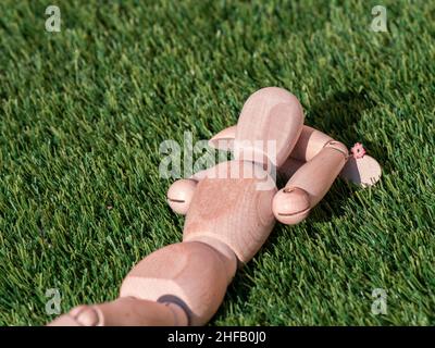 Poupée humaine en bois couchée sur l'herbe, bain de soleil décontracté Banque D'Images