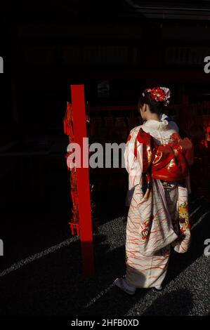 Une jeune femme japonaise traditionnelle vêtue de kimono offrant des prières au sanctuaire de Fushimi Inari-taisha 伏見稲荷大社, Kyoto, Japon. Banque D'Images