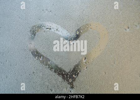 coeur, forme de coeur dessinée à la main sur la surface de verre à la vapeur ou fenêtre avec gouttes de pluie par temps pluvieux. gouttes de pluie sur fenêtre avec espace de copie, sélectif fo Banque D'Images