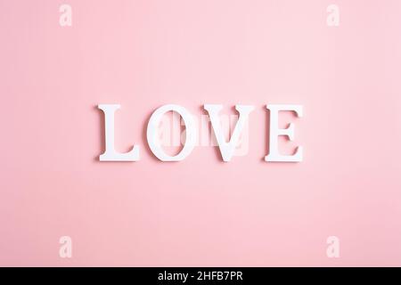 Mot amour fait de lettres blanches sur fond rose.Style minimaliste.Bonne Saint Valentin, fête des mères, concept d'anniversaire. Banque D'Images
