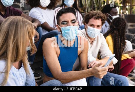 Jeune groupe multiracial d'amis assis sur des escaliers urbains portant un masque chirurgical - concept de style de vie millénaire pour les jeunes Banque D'Images
