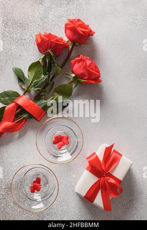Carte de voeux pour la Saint-Valentin avec roses rouges, vin mousseux, cadeau amoureux romantique.Composition verticale.Vue de dessus. Banque D'Images
