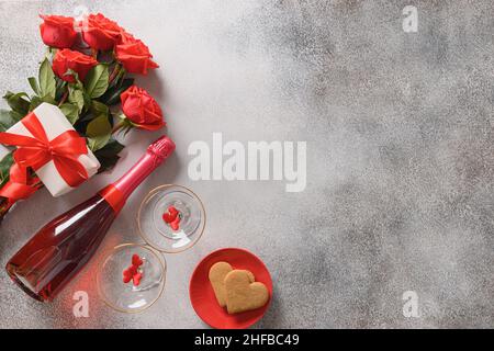 Carte de Saint-Valentin, vin pétillant, cadeau romantique et petits gâteaux en forme de cœur.Vue de dessus.Copier l'espace. Banque D'Images