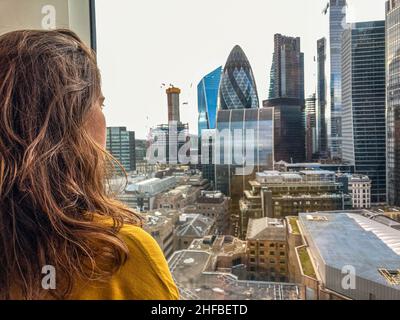 Jeune femme admirant la vue sur la ville de Londres, y compris le Gherkin depuis l'appartement en hauteur de Spitalfields. Banque D'Images