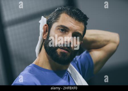 Beau homme essuye la sueur après une séance d'entraînement.Jeune garçon sportif à la fin du match.Un athlète en sueur avec une serviette à la main prête à prendre le spectacle Banque D'Images