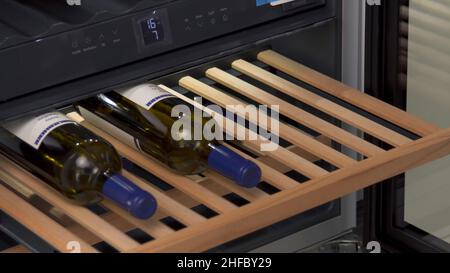 Stockage des bouteilles de vin au réfrigérateur pour refroidir et conserver le vin.Gros plan d'un homme qui fait la démonstration d'un réfrigérateur à vin à la maison dans la boutique d'appareils électroménagers. Banque D'Images