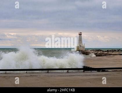 Les vagues se sont écrasent sur la rive par le phare du port de Cobourg lors d'une journée d'hiver houleuse. Banque D'Images