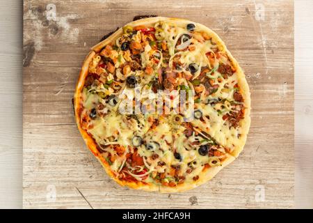 sur une table texturée en bois servi une pizza artisanale avec du fromage, salami, olives, nourriture préparée en studio, style de vie Banque D'Images