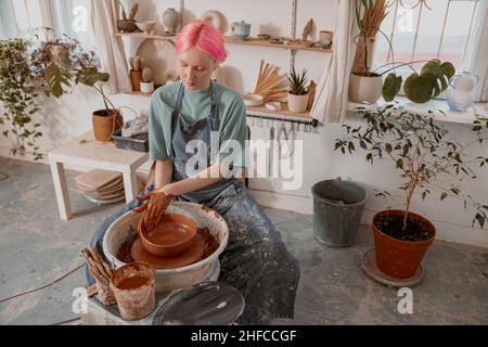 Une femme artisanale se concentre sur un bol de modelage dans la salle de travail Banque D'Images