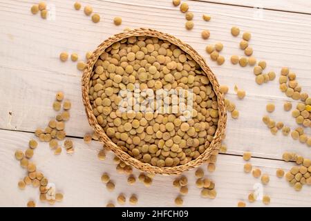 Lentilles vertes bio non cuites avec une plaque de paille sur une table en bois, vue macro, dessus. Banque D'Images