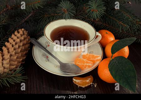 Tasse de thé aux mandarines et branches d'arbre de Noël.Arrière-plan sombre. Banque D'Images