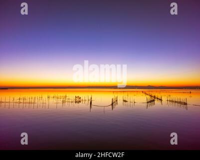 Coucher de soleil dans le lac de l'albufera de Valence (Espagne) avec les filets des pêcheurs dans l'eau.Avec nuances de jaune, orange et violet Banque D'Images