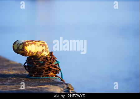 Chaîne rouillée autour du bollard métallique. Banque D'Images