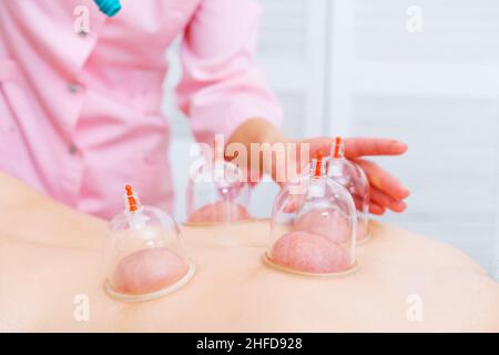 Jeune femme détendue recevant une mise en conserve sur son dos au spa.Massage sous vide.Femme couchée sur sa poitrine avec des canettes sur son dos.Procédure médicale.Médecin professionnel. Banque D'Images