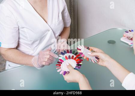 Salon de beauté.Maître avec le client, choisit la couleur du gel vernis dans la salle de manucure.Maître, avec le client, choisit la couleur du vernis à gel.Définissez différentes couleurs de vernis à ongles sur la palette. Banque D'Images