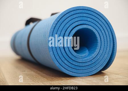 Image rapprochée d'un tapis de yoga bleu couché sur une surface en bois Banque D'Images