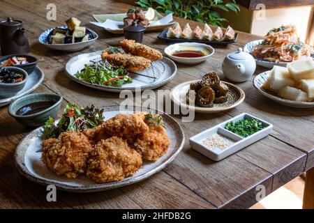 Une variété de plats japonais tels que tonkatsu, gyoza, agedashi tofu, tempura, aubergine frite,servi sur une table rustique Banque D'Images