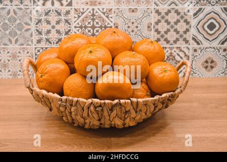 Nombreuses mandarines d'orange dans une table en bois de fond en osier brun.Récolte de mandarines d'agrumes mûres. Banque D'Images