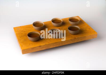 Un ensemble de six tasses traditionnelles pour boire du thé oriental sur une table en bois pour les cérémonies du thé sur fond blanc.Les tasses sont remplies de Banque D'Images