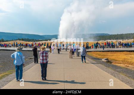 Les gens qui regardent le point chaud volcanique géothermique d'Old Faithful lors d'une éruption d'eau et de vapeur dans le parc de Yellowstone, Wyoming, États-Unis. Banque D'Images