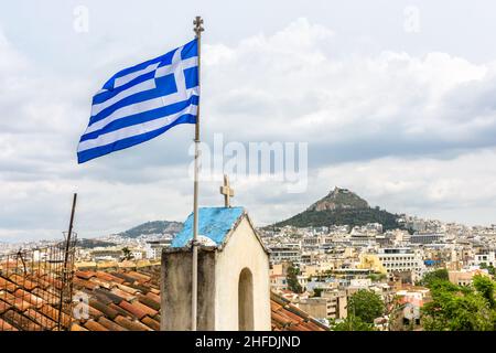 Drapeau grec à Athènes, vue sur le mont Lycabette depuis le quartier de Plaka à pied de l'Acropole, Grèce.C'est l'attraction touristique de la ville.Horizon d'Athènes, nat Banque D'Images