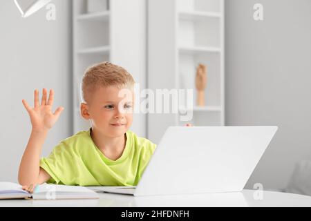 Adorable petit garçon discutant vidéo avec un ordinateur portable à la maison