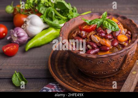 Lobio de viande de bœuf, haricots rouges, oignons, ail, épices et tomates dans un plat en céramique sur fond gris. Cuisine géorgienne Banque D'Images