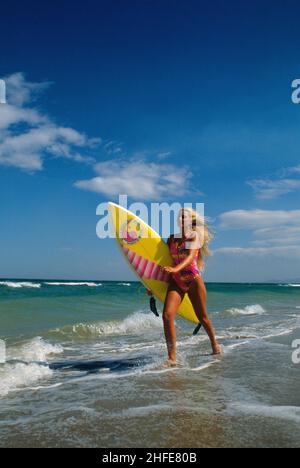 beauté attrayant cheveux blond sportive dos silhouet profil courir sur la plage avec surf surf bleu éclaboussures ciel mer fond Banque D'Images