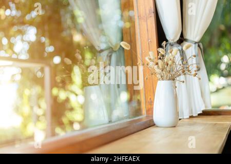 Comptoir de table en bois à côté de la fenêtre décoration avec pot de fleurs séchées dans le café Banque D'Images