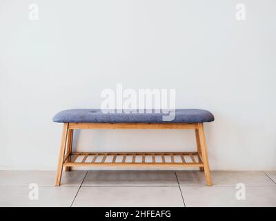 Vide banquette en bois de style minimaliste avec coussin en tissu bleu et étagère en bois sous le siège décorée sur fond blanc vide avec espace pour les copies Banque D'Images