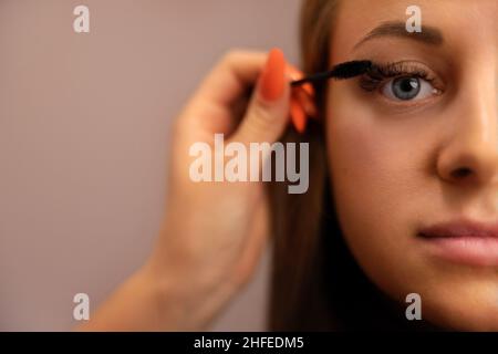 Portrait d'une femme avec la main de cosmétologue utilisant Mascara Banque D'Images