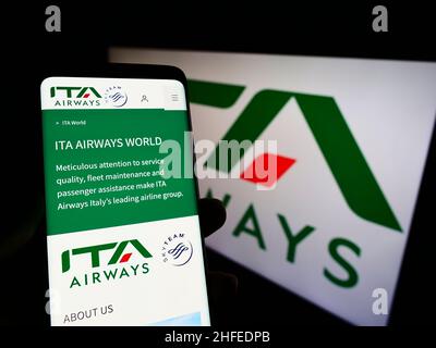 Personne tenant un téléphone portable avec la page web de la compagnie aérienne Italia Trasporto Aereo S.p.A. (ITA Airways) à l'écran avec logo.Concentrez-vous sur le centre de l'écran du téléphone. Banque D'Images