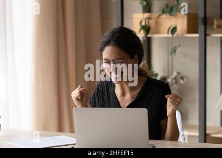 Émotif gai jeune femme célébrant le succès en ligne. Banque D'Images