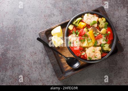 Délicieux ragoût de poisson avec des légumes d'été frais dans un bol sur la table. Vue horizontale du dessus Banque D'Images