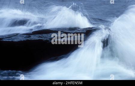 Vue sur les vagues sur les rochers sur la rive, analogique.Pierres, falaises et soleil éclatant.Vent puissant. Banque D'Images