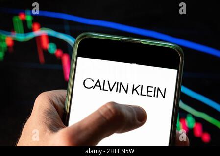 Sur cette photo, le logo de la marque de mode américaine Calvin Klein (CK) est affiché sur un smartphone avec un graphique de l'indice boursier économique en arrière-plan.(Photo de Budrul Chukrut / SOPA Images/Sipa USA) Banque D'Images