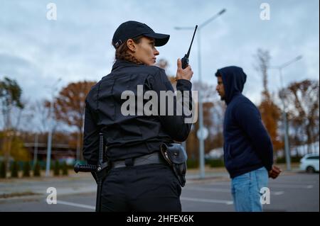 Femme cop utilisant la radio portable vue arrière Banque D'Images