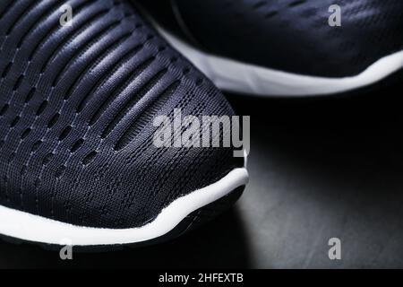 Chaussures de course à pied avec mesh et semelles noires et blanches en gros plan sur fond sombre.Vue de dessus des baskets de sport. Banque D'Images