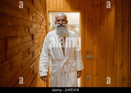 Homme barbu souriant dans un peignoir au sauna Banque D'Images