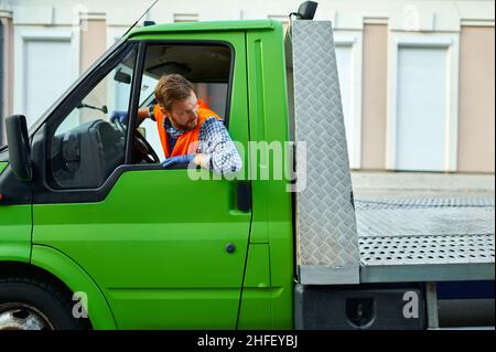 Le conducteur d'un camion de remorquage transporte la voiture dans la rue Banque D'Images