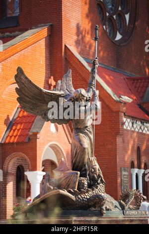 Statue de l'Archange Michel près de l'église catholique rouge de Saint-Simon et Sainte-Hélène sur la place de l'indépendance à Minsk, en Biélorussie Banque D'Images