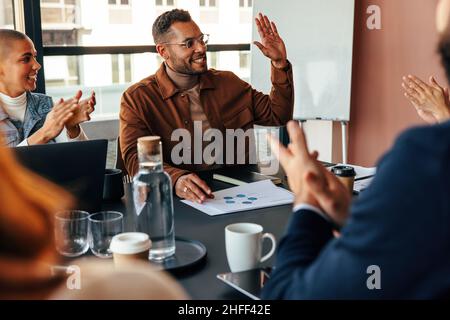 les gens d'affaires applaudissent leur collègue dans une salle de réunion. Groupe de gens d'affaires multiethniques applaudissant joyeusement pendant leur réunion du matin. Successfu Banque D'Images