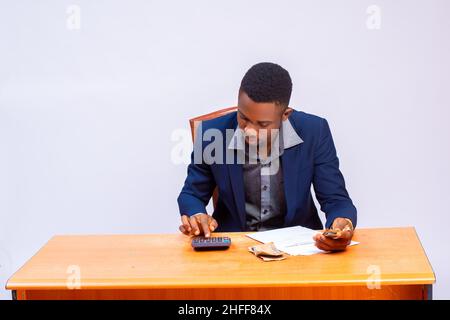 un jeune homme d'affaires africain charmant isolé sur fond blanc calculant sa facture Banque D'Images