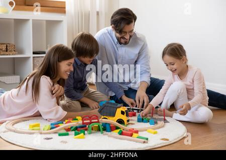 Couple et enfants jouant du chemin de fer en bois et des cubes à la maison Banque D'Images