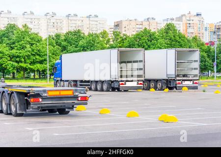 Camions avec remorques à conteneurs ouverts dans le stationnement de l'entrepôt en attente de chargement dans le vol, marchandises pour livraison Banque D'Images