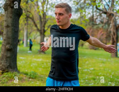 Coureur de sport noir s'étirant les bras avant de faire l'entraînement matinal dans le parc public Banque D'Images
