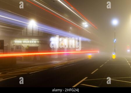 Pub britannique, The Fleece Inn, tourné dans le brouillard du matin montrant de légères stries de voitures qui passent. Banque D'Images